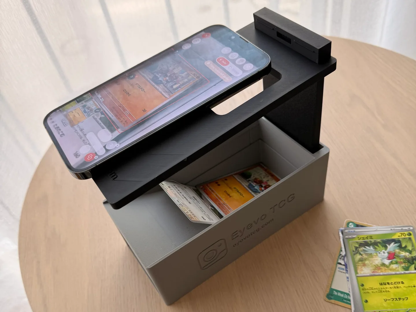 Julian’s printed Eyevo scanner box with a phone above a Japanese Pokémon card